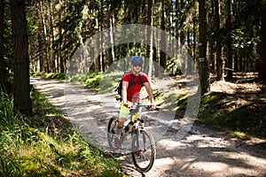 Young athlete man with helmet and red t-shirt riding a bicycle on the road. Enjoying sport in nature