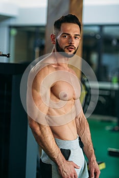 Young athlete posing with a torso for photography on a brick wall background. Bodybuilder, athlete with pumped muscles.