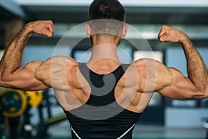 Young athlete posing with a torso for photography on a brick wall background. Bodybuilder, athlete with pumped muscles.