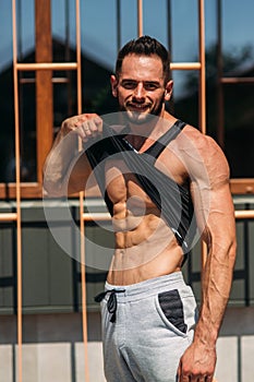 Young athlete posing with a torso for photography on a brick wall background. Bodybuilder, athlete with pumped muscles.