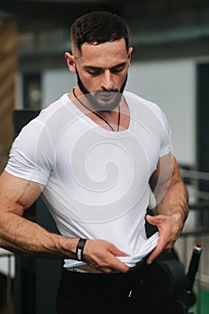 Young athlete posing with a torso for photography in gym. Bodybuilder, athlete with pumped muscles, breast and arm