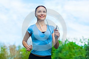 Young athlete running in the park and listens to music in summer, morning exercise.