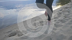 A young athlete runs on the beach at sunset. Athletic girl doing sports on the street