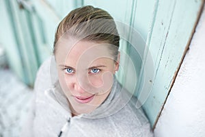 A young athlete stands in front of a turquoise door looking up into the camera