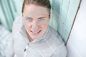 A young athlete stands in front of a turquoise door looking up into the camera