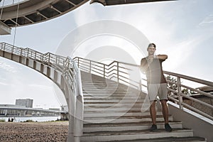 A young athlete stands on the stairs and looks at his smart watch