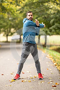 A young athlete is warming up before running training in the park