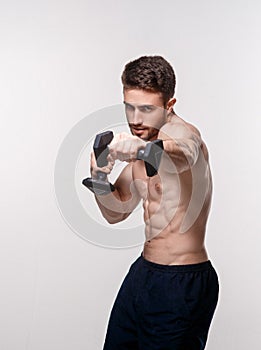 Young athlete on a white background lifts dumbbells. training a bearded man athletic build