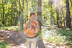 Young athlete woman checking fitness progress on her smart watch. Female runner using fitness app to monitor workout