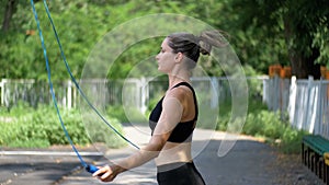 Young Athlete Woman in Comfortable Sport Outfit Jumping Rope on a Sports Field in the Park