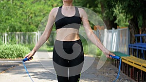 Young Athlete Woman in Comfortable Sport Outfit Jumping Rope on a Sports Field in the Park