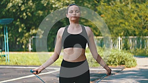 Young Athlete Woman in Comfortable Sport Outfit Jumping Rope on a Sports Field in the Park