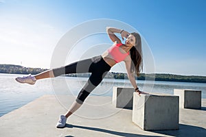 Young athlete woman doing a push up  near the lake. Sport and training concepts