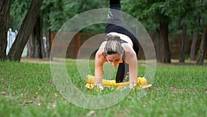 Young athlete woman in sport outfit engaged practicing yoga lying on a carpet in a park on a green lawn