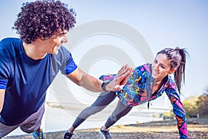 Young athletes giving high five to each other while doing push u