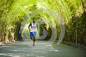 Young athletic and attractive black African American runner man doing running workout training outdoors on urban city park in