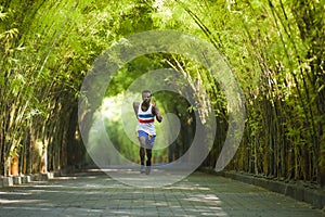 Young athletic and attractive black African American runner man doing running workout training outdoors on urban city park in