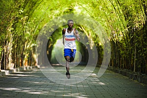 Young athletic and attractive black African American runner man doing running workout training outdoors on urban city park in