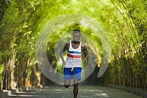 Young athletic and attractive black afro American runner man doing running workout training outdoors on urban city park in fitness