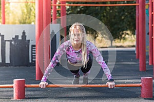 Young, athletic and beautiful girl doing push-ups on the sports ground.