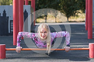 Young, athletic and beautiful girl doing push-ups on the sports ground.