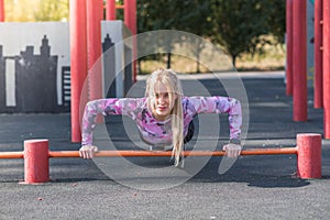 Young, athletic and beautiful girl doing push-ups on the sports ground.