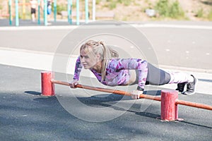 Young, athletic and beautiful girl doing push-ups on the sports ground.