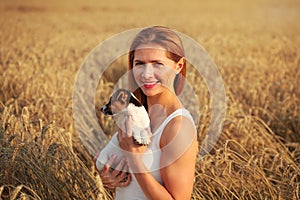 Young athletic brunette woman smiling, holding Jack Russell terr