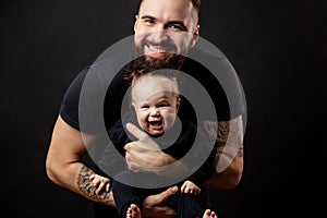 Young athletic father with adorable baby on black background