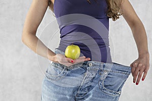 Young athletic female silhouette, apple and old big pants