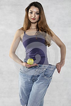 Young athletic female silhouette, apple and old big pants