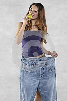 Young athletic female silhouette, apple and old big pants