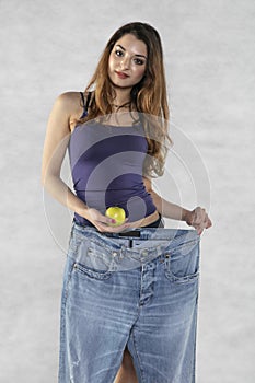 Young athletic female silhouette, apple and old big pants