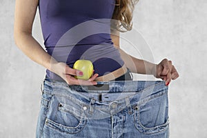 Young athletic female silhouette, apple and old big pants