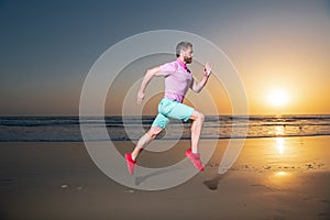 Young athletic and fit american sport man doing running workout on sunset at the beach training jogging barefoot in