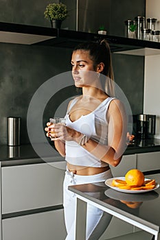 Young athletic girl drinks fresh orange juice in the morning