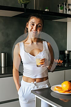 Young athletic girl drinks fresh orange juice in the morning