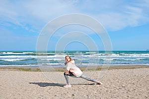 Young athletic girl makes gymnastic figures on the beach.