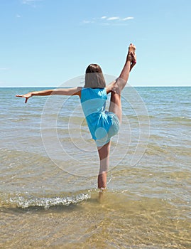 Young athletic girl Perform rhythmic gymnastics exercises on the sea water