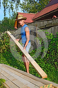 Young athletic man in balomenou hat puts a pine Board on the sta