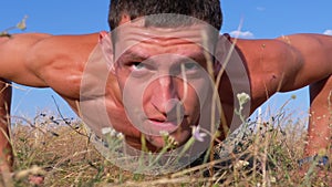 Young Athletic Man with a Bare Torso Performs Pushups on the Nature