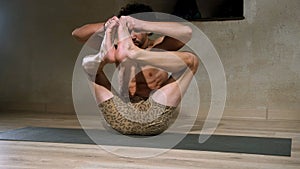 A young and athletic man does yoga and performs asanas.