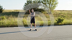 Young athletic man doing body warm-up outdoors in sunny day