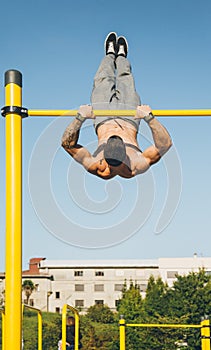 Young athletic man doing gymnastics on bars at a calisthenics park photo