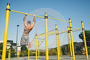 Young athletic man doing gymnastics on bars at a calisthenics park photo