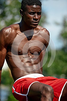 Young athletic man doing push-ups. Fitness model doing outdoor workout. Muscular and strong guy exercising.