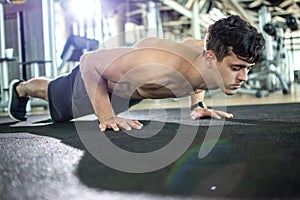 Young athletic man doing push ups in the gym.