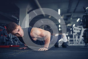 Young athletic man doing push-ups in gym. Muscular and strong gu