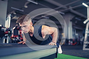 Young athletic man doing push-ups in gym. Muscular and strong gu