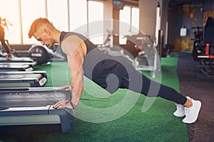 Young athletic man doing push-ups in gym. Muscular and strong gu